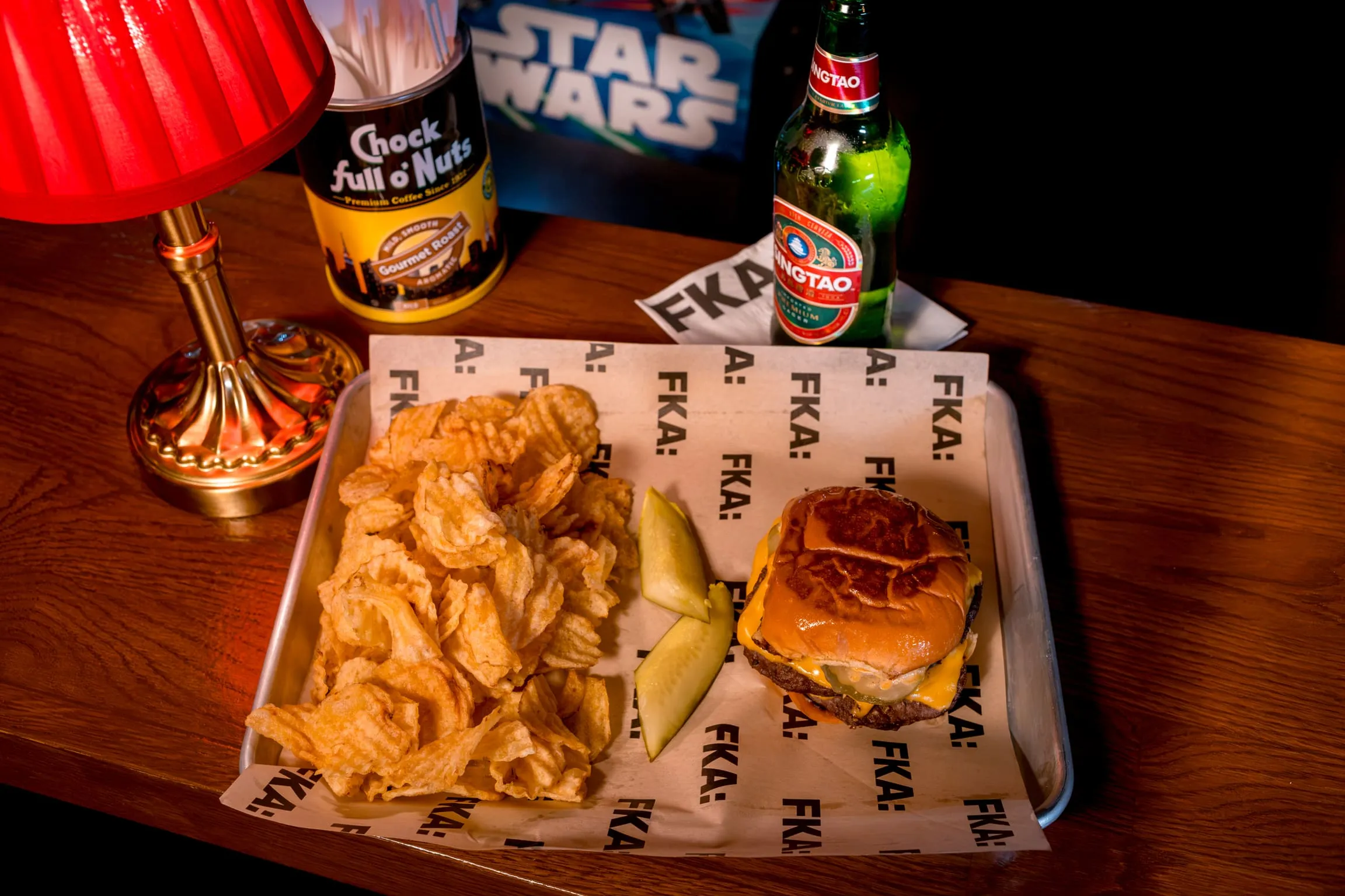 Overhead of the Royale With Cheese burger with ruffle chips and pickles on a paper-lined tray at FKA: Formerly Known As