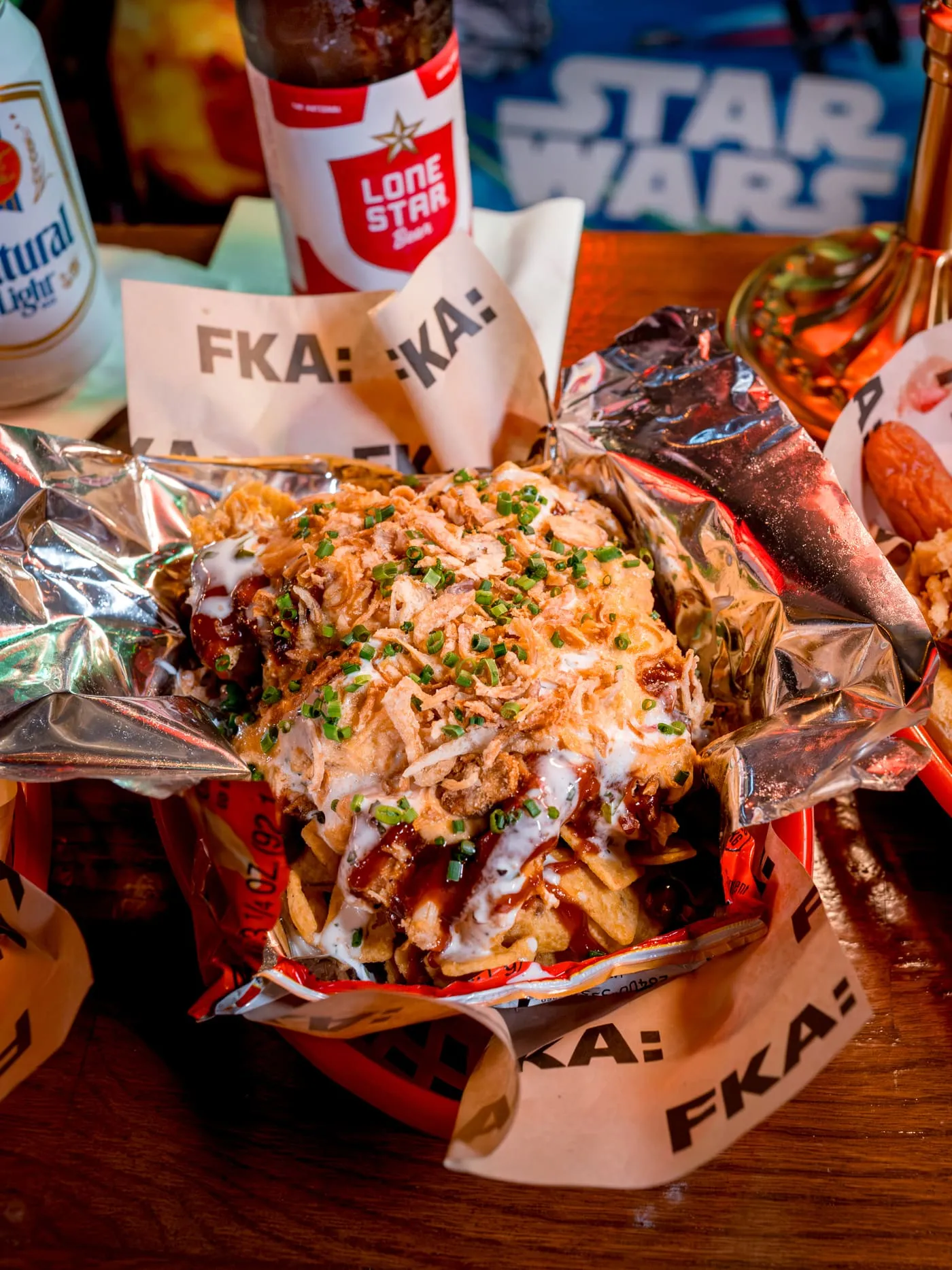 The Frito-Pie, loaded with smoked pulled pork, cheese sauce, and crispy onions, with cans of beer at FKA: Formerly Known As